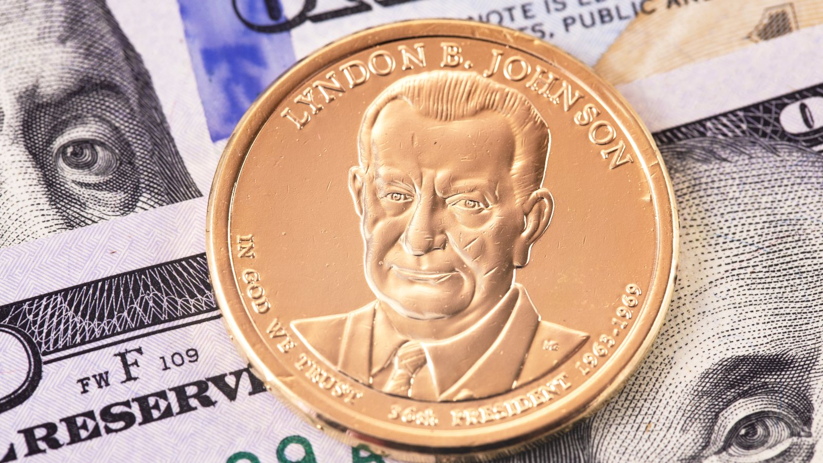 one dollar golden coin with Lyndon Baines Johnson portrait, and hundred dollars banknotes